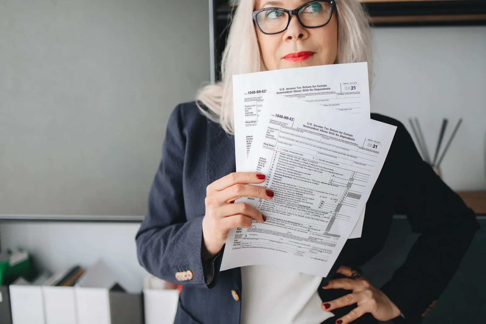Businesswoman presenting tax documents in a modern office setting. Acquisition financing requirements: documents to gather